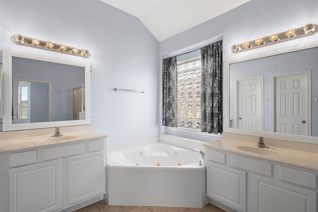 12610 Hobbs Terrace Dr, Tomball, TX 77377 - bathroom featuring two vanities, a jetted tub, vaulted ceiling, and tile patterned floors