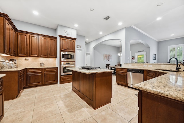 1114 Commons Waterway Dr, Huffman, TX 77336 - kitchen featuring appliances with stainless steel finishes, arched walkways, tasteful backsplash, light stone countertops, and ornamental molding