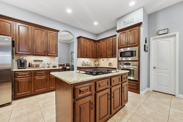 1114 Commons Waterway Dr, Huffman, TX 77336 - kitchen with stainless steel appliances, decorative backsplash, light stone countertops, arched walkways, and recessed lighting