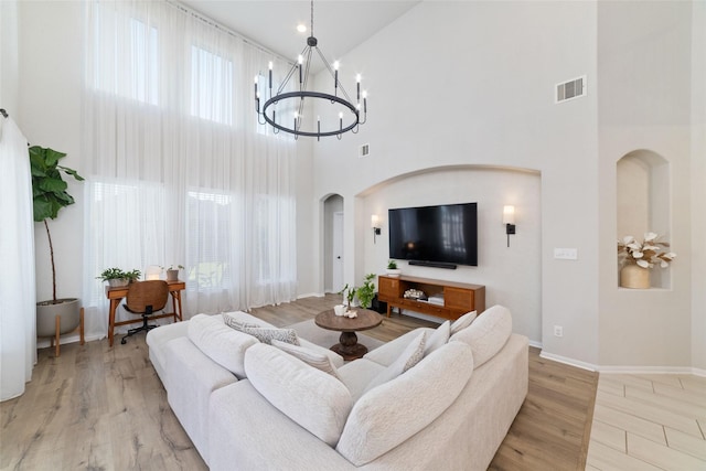 18534 Tall Woods Pl, Houston, TX 77084 - living area with a towering ceiling, arched walkways, healthy amount of natural light, a chandelier, and light wood-type flooring