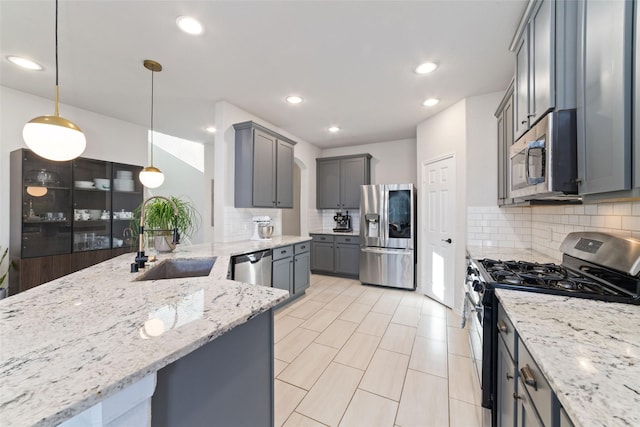 18534 Tall Woods Pl, Houston, TX 77084 - kitchen with stainless steel appliances, light stone counters, backsplash, gray cabinetry, and recessed lighting