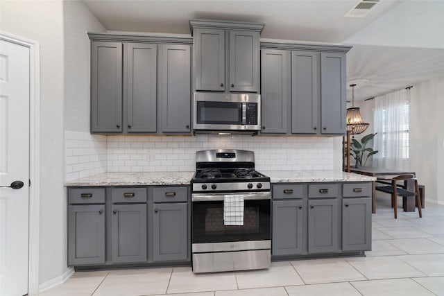 18534 Tall Woods Pl, Houston, TX 77084 - kitchen featuring appliances with stainless steel finishes, gray cabinets, tasteful backsplash, light stone counters, and light tile patterned floors