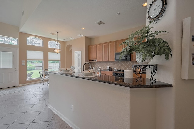 15902 Mill Canyon Ct, Cypress, TX 77429 - kitchen with black microwave, tasteful backsplash, arched walkways, stainless steel range with gas cooktop, and light tile patterned flooring