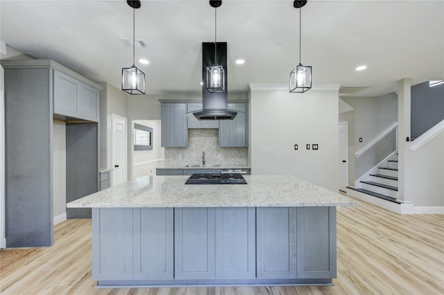 13727 Sablegarden Ln, Houston, TX 77014 - kitchen with gray cabinets, tasteful backsplash, light stone countertops, light wood-type flooring, and a kitchen island