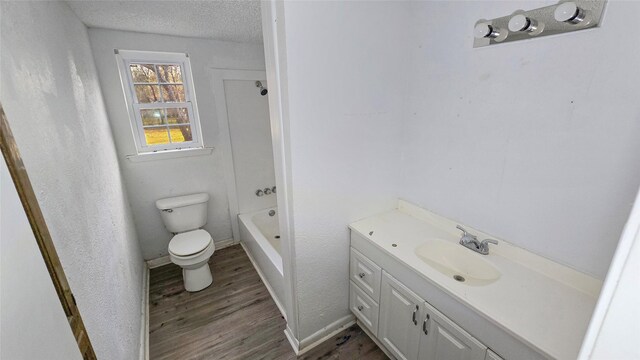 242 Bishop, Livingston, TX 77351 - bathroom with wood finished floors, vanity, a textured ceiling, and washtub / shower combination