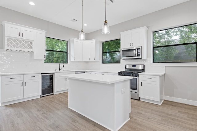 806 E 39th St Unit A, Houston, TX 77022 - kitchen featuring beverage cooler, appliances with stainless steel finishes, decorative backsplash, light wood finished floors, and light countertops