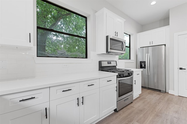 806 E 39th St Unit A, Houston, TX 77022 - kitchen with stainless steel appliances, backsplash, white cabinetry, light wood-style flooring, and light countertops