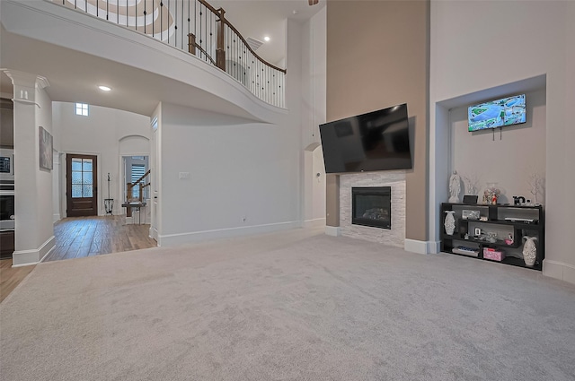 9011 Bright Harbor Dr, Cypress, TX 77433 - unfurnished living room featuring a towering ceiling, a glass covered fireplace, carpet, wood finished floors, and recessed lighting