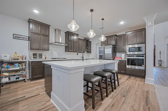 9011 Bright Harbor Dr, Cypress, TX 77433 - kitchen with appliances with stainless steel finishes, wall chimney range hood, dark brown cabinets, tasteful backsplash, and recessed lighting