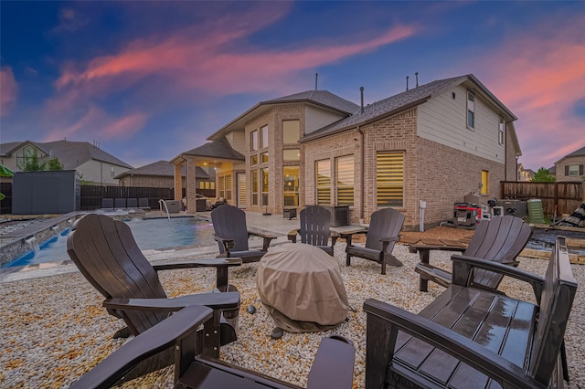 9011 Bright Harbor Dr, Cypress, TX 77433 - patio terrace at dusk featuring a patio, a fenced backyard, a storage shed, and a fire pit