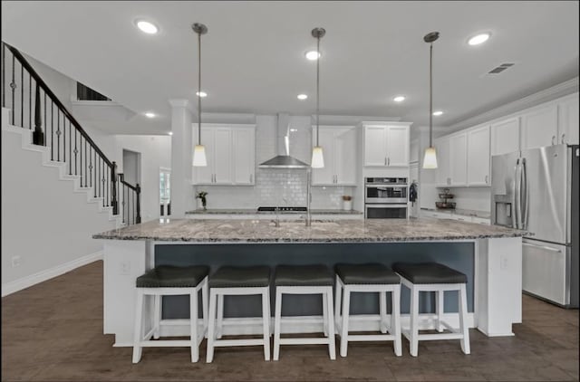 25119 Dunbrook Springs Ln, Katy, TX 77494 - kitchen with stainless steel appliances, wall chimney range hood, a large island, white cabinets, and recessed lighting