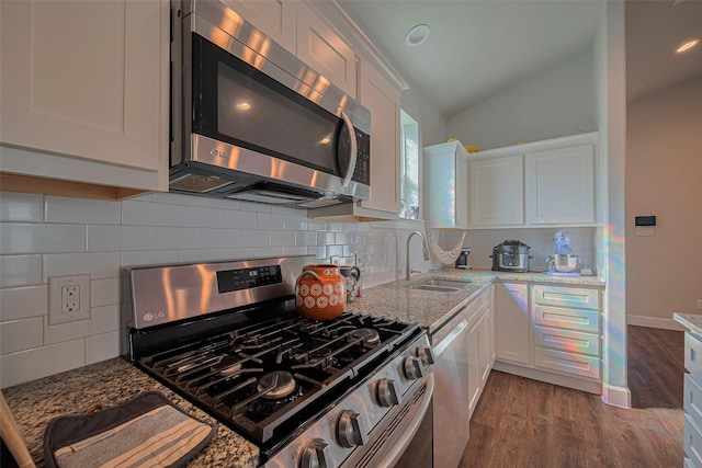 6418 Gresham St, Wallis, TX 77485 - kitchen featuring stainless steel appliances, white cabinets, light stone countertops, vaulted ceiling, and wood finished floors
