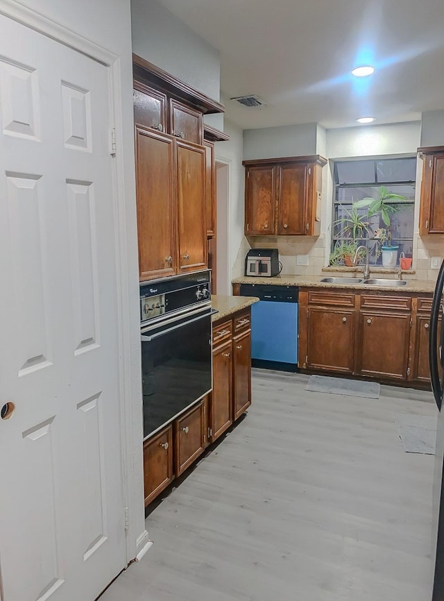 16510 De Lozier St, Jersey Village, TX 77040 - kitchen with black oven, dishwasher, light wood finished floors, and tasteful backsplash