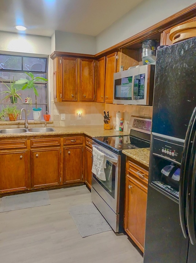 16510 De Lozier St, Jersey Village, TX 77040 - kitchen with stainless steel appliances, light wood-type flooring, brown cabinetry, and backsplash