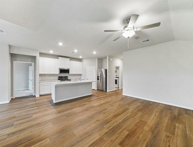 21622 Teton Rock Trl, Richmond, TX 77407 - kitchen featuring appliances with stainless steel finishes, open floor plan, ceiling fan, tasteful backsplash, and light wood-style floors