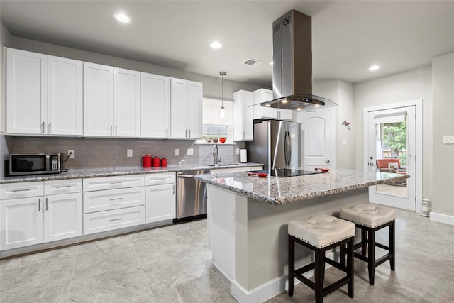 224 Evergreen Dr, Huntsville, TX 77340 - kitchen featuring appliances with stainless steel finishes, island range hood, backsplash, white cabinetry, and light stone countertops
