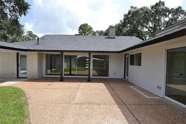 5330 Dumfries Dr, Houston, TX 77096 - rear view of house with a patio, a shingled roof, a chimney, and brick siding