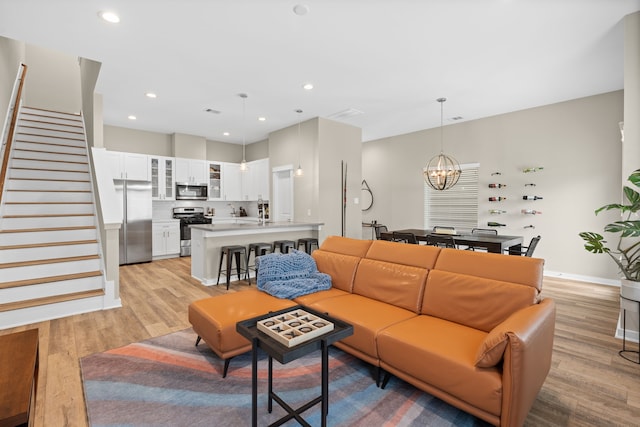 413 Stonework Oaks Ln, Houston, TX 77076 - living area with stairway, a chandelier, light wood-style flooring, and recessed lighting