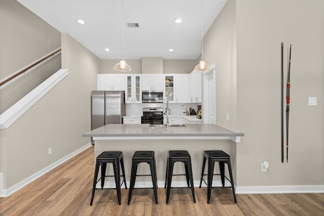 413 Stonework Oaks Ln, Houston, TX 77076 - kitchen featuring stainless steel appliances, a kitchen bar, a peninsula, white cabinetry, and recessed lighting