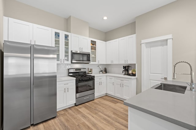 413 Stonework Oaks Ln, Houston, TX 77076 - kitchen with stainless steel appliances, white cabinets, backsplash, light wood finished floors, and recessed lighting
