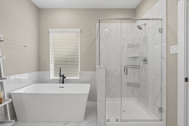 413 Stonework Oaks Ln, Houston, TX 77076 - full bath featuring marble tiled flooring, a freestanding tub, a marble finish shower, a wainscoted wall, and tile walls