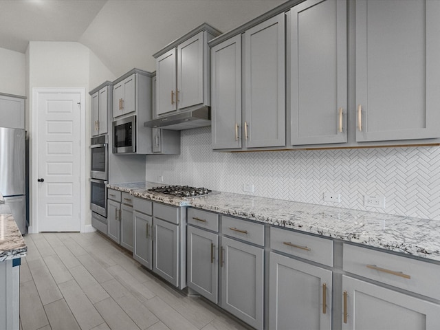706 Westwood Dr, League City, TX 77573 - kitchen with gray cabinets, appliances with stainless steel finishes, backsplash, under cabinet range hood, and lofted ceiling
