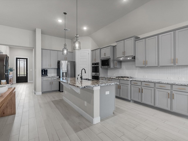 706 Westwood Dr, League City, TX 77573 - kitchen featuring gray cabinets, stainless steel appliances, under cabinet range hood, backsplash, and light stone countertops
