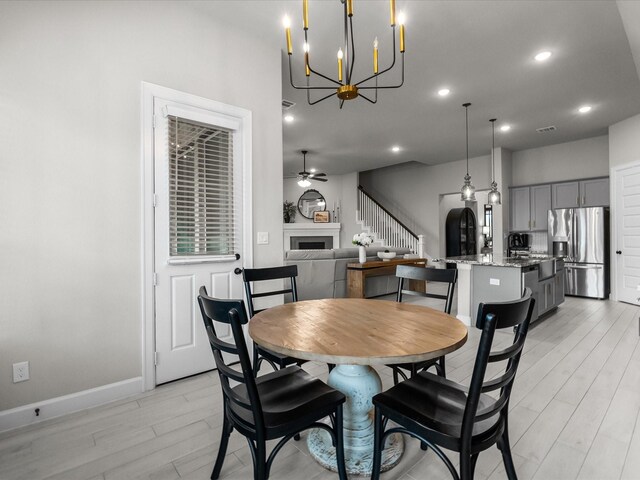 706 Westwood Dr, League City, TX 77573 - dining room with light wood finished floors, a chandelier, recessed lighting, a fireplace, and ceiling fan