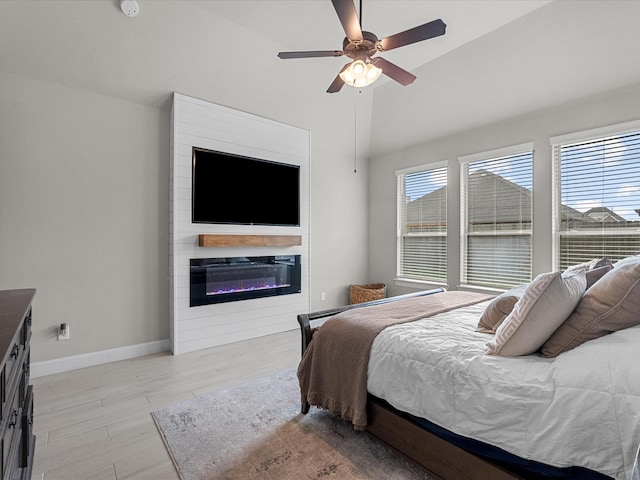 706 Westwood Dr, League City, TX 77573 - bedroom featuring a glass covered fireplace, wood finished floors, lofted ceiling, and a ceiling fan