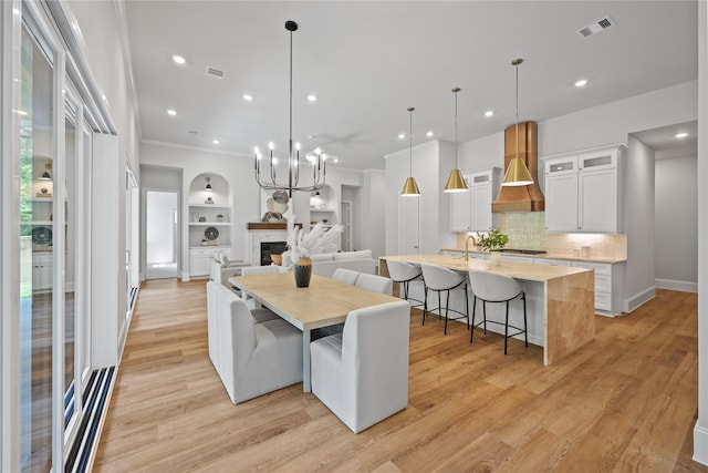 161 Pine Branch Dr, Montgomery, TX 77356 - dining area featuring light wood-style flooring, a fireplace, recessed lighting, built in shelves, and a chandelier