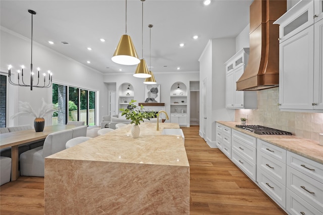 161 Pine Branch Dr, Montgomery, TX 77356 - kitchen with custom exhaust hood, stainless steel gas cooktop, crown molding, open floor plan, and a chandelier