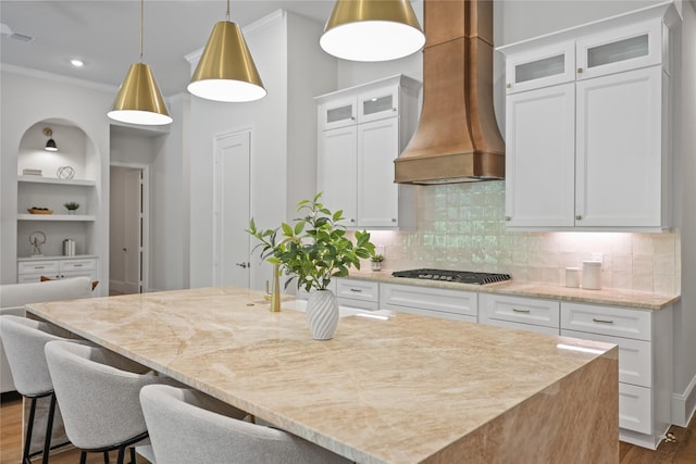 161 Pine Branch Dr, Montgomery, TX 77356 - kitchen featuring custom range hood, stainless steel gas cooktop, ornamental molding, light stone counters, and a center island