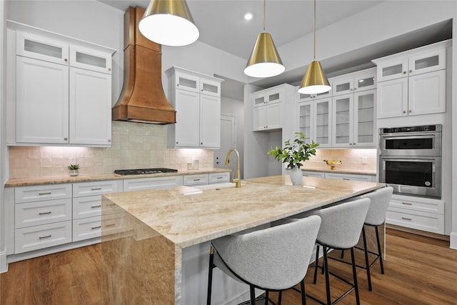 161 Pine Branch Dr, Montgomery, TX 77356 - kitchen with stainless steel appliances, backsplash, light stone counters, an island with sink, and white cabinets