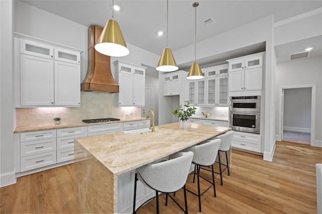 161 Pine Branch Dr, Montgomery, TX 77356 - kitchen featuring custom exhaust hood, appliances with stainless steel finishes, backsplash, an island with sink, and light stone counters