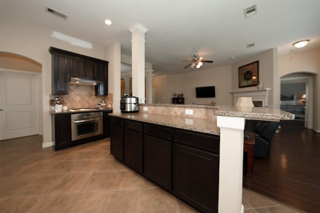 28407 Kinglet Pines Dr, Katy, TX 77494 - kitchen with oven, open floor plan, ceiling fan, backsplash, and light stone counters