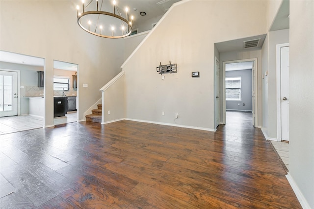 1927 Vermillion View St, Fresno, TX 77545 - unfurnished living room featuring wood finished floors, a towering ceiling, stairs, and a chandelier