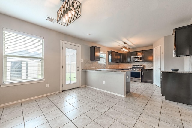 1927 Vermillion View St, Fresno, TX 77545 - kitchen with stainless steel appliances, tasteful backsplash, healthy amount of natural light, and a peninsula