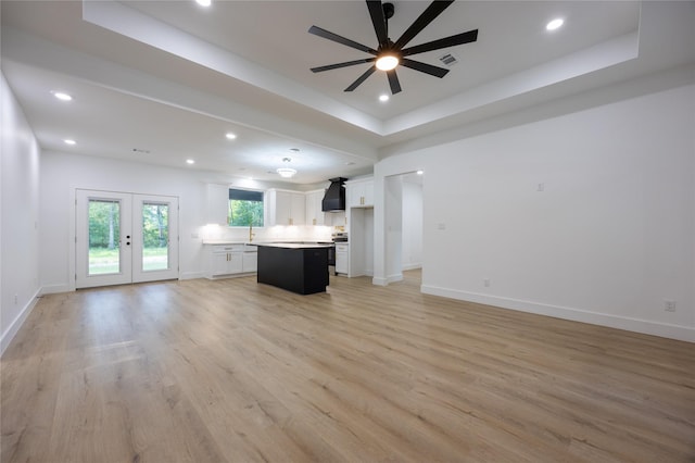 51 V Allen Ln, Coldspring, TX 77331 - unfurnished living room with a ceiling fan, light wood-type flooring, recessed lighting, a tray ceiling, and french doors