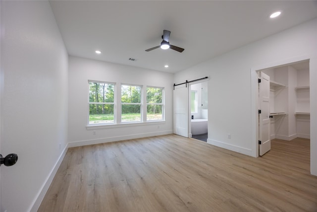 51 V Allen Ln, Coldspring, TX 77331 - unfurnished bedroom with a barn door, wood finished floors, a walk in closet, recessed lighting, and ensuite bathroom