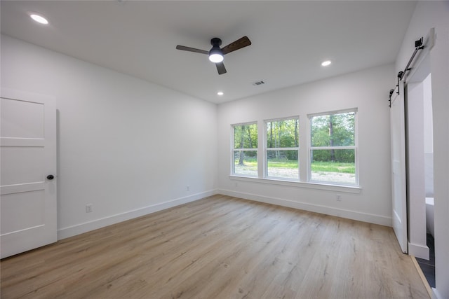 51 V Allen Ln, Coldspring, TX 77331 - empty room featuring a barn door, ceiling fan, light wood-style floors, and recessed lighting