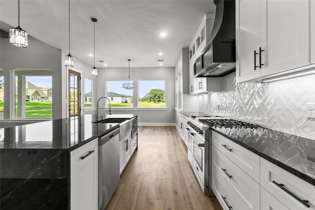210 Hogan Ln, Hempstead, TX 77445 - kitchen with stainless steel appliances, wall chimney exhaust hood, wood finished floors, backsplash, and dark stone countertops