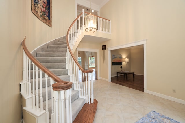 9327 Tranquil Park Dr, Spring, TX 77379 - stairs with a chandelier, a high ceiling, tile patterned floors, and crown molding