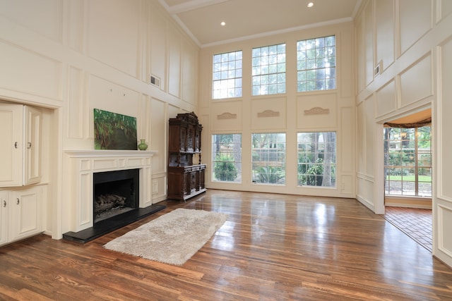 9327 Tranquil Park Dr, Spring, TX 77379 - unfurnished living room featuring a decorative wall, a high ceiling, a fireplace with raised hearth, healthy amount of natural light, and dark wood-style floors