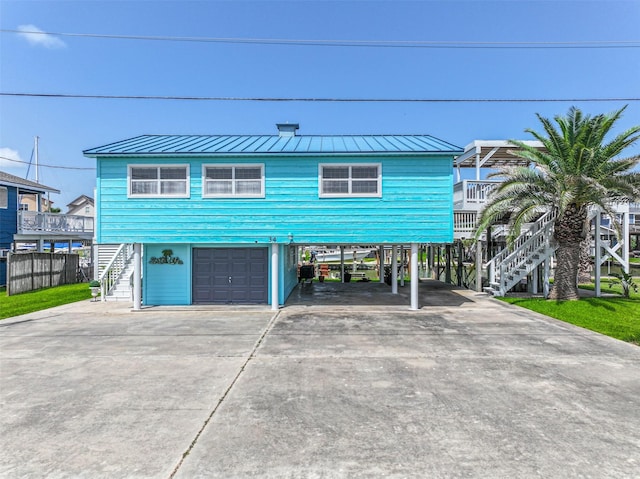 34 Tarpon Ln, Freeport, TX 77541 - view of front of house with stairway, driveway, a carport, a garage, and a standing seam roof