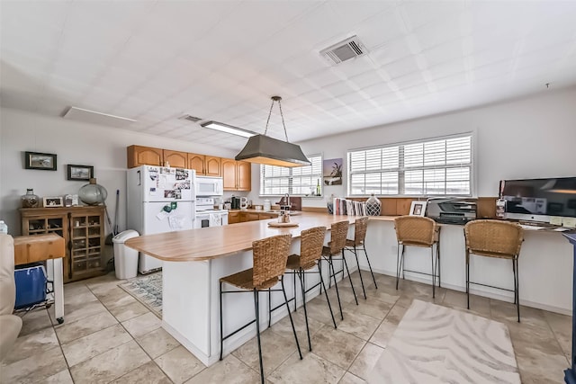 34 Tarpon Ln, Freeport, TX 77541 - kitchen with white appliances, a kitchen bar, a peninsula, light tile patterned flooring, and decorative light fixtures