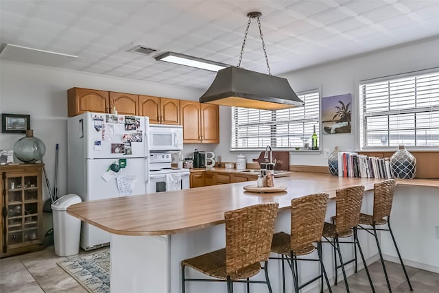 34 Tarpon Ln, Freeport, TX 77541 - kitchen with white appliances, a peninsula, a breakfast bar area, and light tile patterned floors