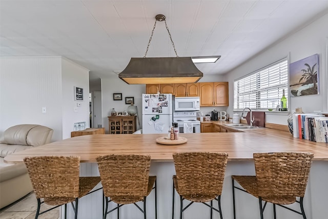 34 Tarpon Ln, Freeport, TX 77541 - kitchen with white appliances, a peninsula, a breakfast bar area, light countertops, and light brown cabinets