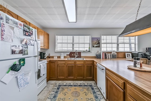34 Tarpon Ln, Freeport, TX 77541 - kitchen featuring white appliances, light countertops, brown cabinets, a peninsula, and light tile patterned flooring