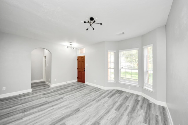 7427 Oakwood Canyon Dr, Cypress, TX 77433 - unfurnished room with a chandelier, arched walkways, and light wood-style floors