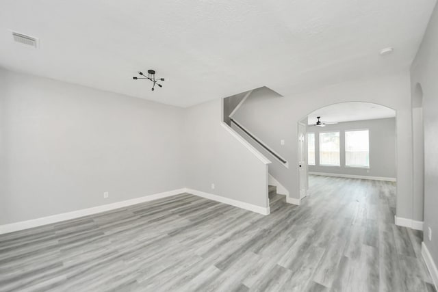 7427 Oakwood Canyon Dr, Cypress, TX 77433 - spare room featuring arched walkways, light wood-type flooring, stairway, a smoke detector, and ceiling fan